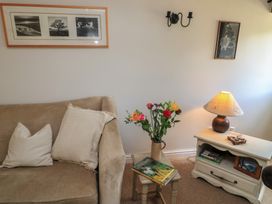 A living room with a sofa, flower vase, and side table at 2 The Gardens in Lechlade