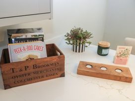 A kitchen with books in a wooden box and a potted plant at 2 The Gardens Lechlade