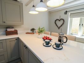 A kitchen with a counter, coffee maker, cups, and strawberries at 2 The Gardens in Lechlade