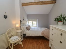 A bedroom with a bed and a chair at 2 The Gardens in Lechlade