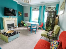A living room with a television, table, and seating area at Flat 3 in Llandudno