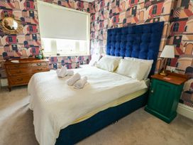 A bedroom with a blue bed, nightstand and dresser at Flat 3 in Llandudno