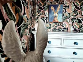 A bedroom with a rabbit statue and floral wallpaper at Flat 3 in Llandudno