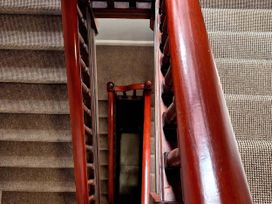 A staircase with a wooden handrail and carpet at Flat 3 in Llandudno
