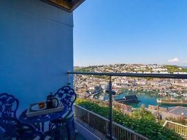 A balcony with a table and chairs overlooking a harbor at Trewollock in Mevagissey
