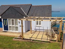 A house with a pergola and bench overlooking water at Trewollock in Mevagissey