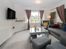A living room with a sofa and television at Courtyard Cottage