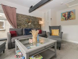 A living room with a sofa, armchair, and table at Courtyard Cottage 