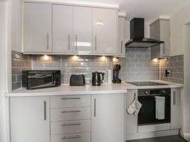 A kitchen with appliances and cabinets at Courtyard Cottage