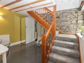 A hallway with stairs and kitchen appliances at Courtyard Cottage
