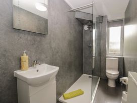 A bathroom with a sink, toilet, shower, and mirror at Courtyard Cottage
