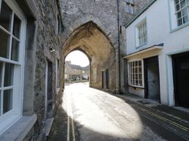 An arched doorway with stone walls and buildings on either side at Courtyard Cottage