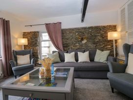 A living room with a gray sofa and armchair at Courtyard Cottage in Cartmel