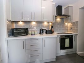 A kitchen with modern appliances at Courtyard Cottage cartmel