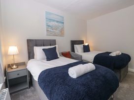 A bedroom with two beds and a painting at Courtyard Cottage, Cartmel