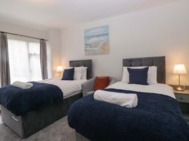 A bedroom with two beds and a painting at Courtyard Cottage in Cartmel