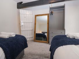 A bedroom with two beds and a mirror at Courtyard Cottage in Cartmel