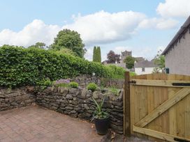 An outdoor garden with a stone wall and gate at Courtyard Cottage in Cartmel