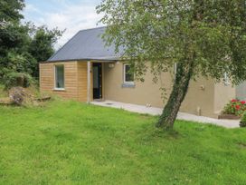 An outdoor view of a house with a door and windows at Mayfly Cottage