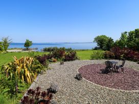 A garden with a table and chairs overlooking the water at Mayfly Cottage
