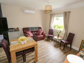 A living room with a sofa and dining table at Mayfly Cottage