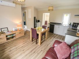 A living room and kitchen area with furniture at Mayfly Cottage