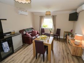 A living room with a sofa and dining table at Mayfly Cottage