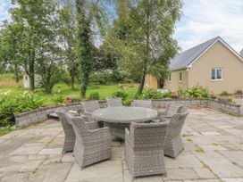 An outdoor patio with a circular table and chairs at Mayfly Cottage