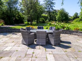An outdoor seating area with a table and chairs at Mayfly Cottage in 