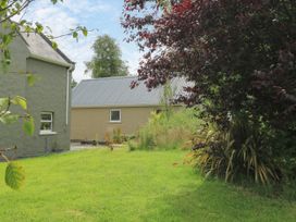 A garden with a house and greenery at Mayfly Cottage in 