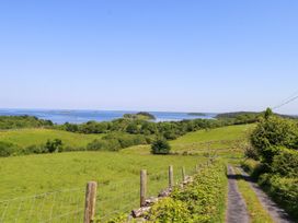 A view of a grassy landscape with a road and water at Mayfly Cottage