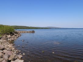 A shoreline with rocks and water at Mayfly Cottage