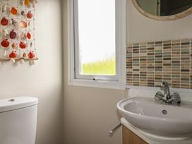 A bathroom with a sink, toilet, and window at Tucked Away in Newquay