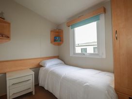 A bedroom with a single bed and shelves at Tucked Away in Newquay