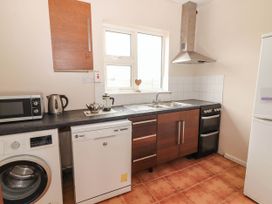 A kitchen with a washing machine, dishwasher, and microwave at Golf Club View in County Clare