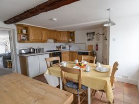 A kitchen with wooden cabinets and a dining table at Little Wickers in Wareham