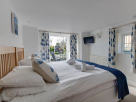 A bedroom with a bed and curtains overlooking a garden at Little Wickers in Wareham