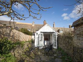 A garden with a patio and chairs at Little Wickers in Wareham