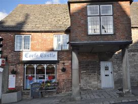 A storefront of Corfe Castle Village Stores with a sign and columns in Wareham