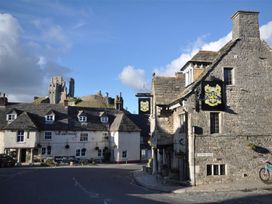 A pub and stone buildings in a street with a castle in the background at Little Wickers in Wareham