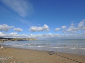 A beach with sand and water under a blue sky at Little Wickers in Wareham