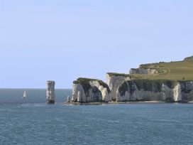 Cliffs on the coast with a sailboat in the ocean at Little Wickers Wareham