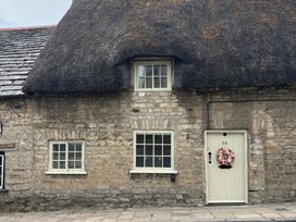 The exterior of a thatched cottage with stone walls at Little Wickers in Corfe Castle