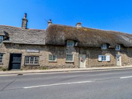 A thatched cottage with stone walls and front door at Little Wickers in Corfe Castle
