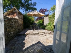 A patio with a table and chairs under an umbrella at Little Wickers in Corfe Castle