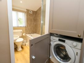 A bathroom with a toilet, bathtub, sink, and washing machine at Little Wickers in Corfe Castle