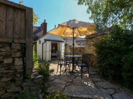 A garden with a table and chairs under an umbrella at Little Wickers in Corfe Castle