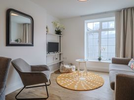 A living room with a mirror, sofa, and television at Flat 1 Harley House in Sidmouth