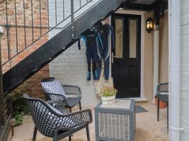 An outdoor area with a door, wetsuits hanging and seating at Flat 1 Harley House Sidmouth