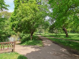 A park with trees and a pathway near a body of water at Flat 1 Harley House in Sidmouth